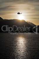 Helicopter flying over the sea at sunset