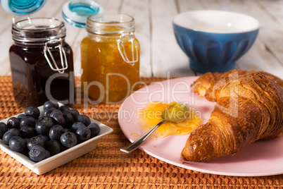 Breakfast with croissant and blueberries over a tablecloth