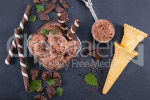 Scoops chocolate ice cream in glass bowl with wafer sticks, cone