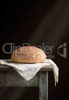 baked round rye bread lies on a gray linen napkin