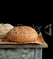 baked round rye bread lies on a brown paper