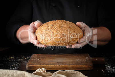 male hands are holding brown baked rye bread