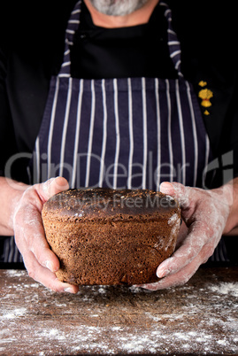 male hands are holding brown baked rye bread