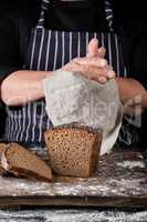 chef in black uniform sliced baked rye bread on a brown wooden b