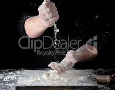 chef in black uniform sifts through his fingers white wheat flou