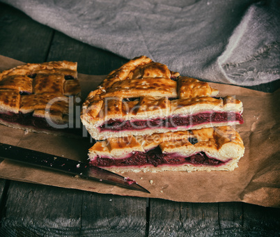 baked pieces of cake with cherries lie on brown paper