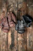 two pairs of leather vintage boxing gloves hanging on a nail
