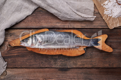 fresh whole sea bass fish on brown cutting board