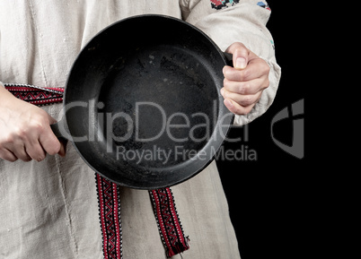 woman in a gray linen dress holds a round cast-iron pan