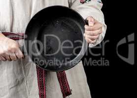 woman in a gray linen dress holds a round cast-iron pan