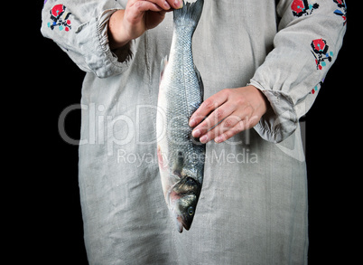 woman in gray linen clothes holding a fresh sea bass fish