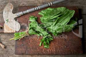 green sorrel leaves on an old brown wooden board and an old iro