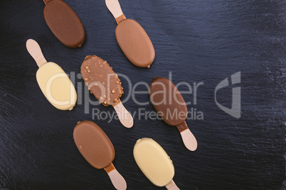 Ice cream on stick covered with chocolate on black slate
