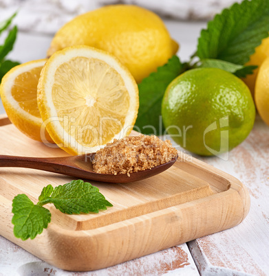wooden spoon with brown sugar on the board, lemons and lime, min