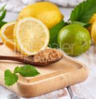 wooden spoon with brown sugar on the board, lemons and lime, min