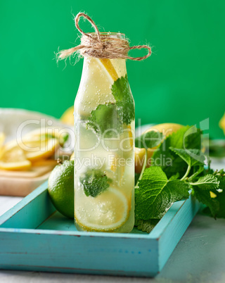cold drink with lemons, mint leaves, lime in a glass bottle