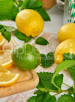 ripe yellow lemons and lime, mint green on a white wooden board