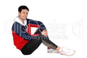 Happy young man sitting on the floor resting from exercise