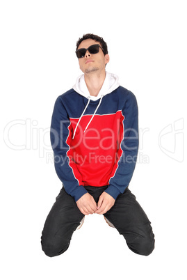 Young man in sports clothing kneeling on the floor