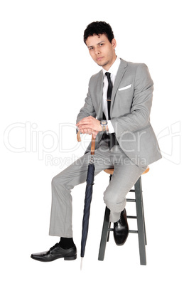 Young bossiness man sitting in a gray suit