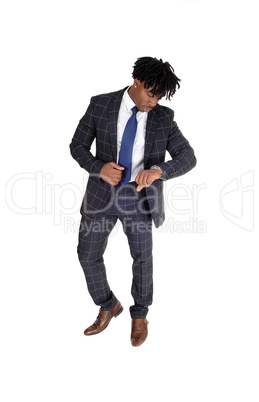 Relaxed black man standing in a suit looking at his watch