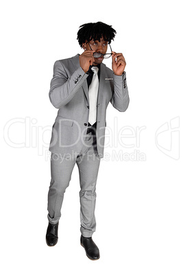 A black young man standing in a gray suit and sunglasses