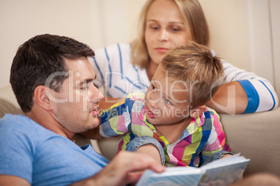 Curious little boy with mum and dad. Reading book together