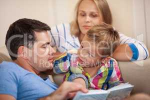 Curious little boy with mum and dad. Reading book together