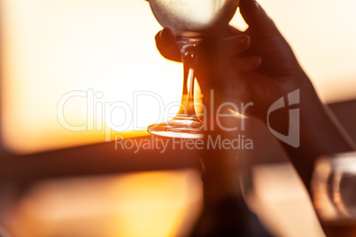 Wineglass in female hand against the sunset