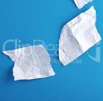 crumpled empty torn pieces of white paper on a blue background