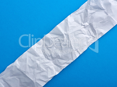 strip of crumpled blank white paper on a blue background