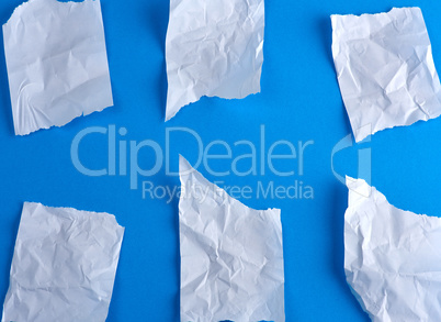 crumpled empty torn pieces of white paper on a blue background