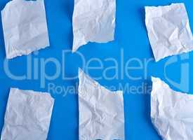 crumpled empty torn pieces of white paper on a blue background
