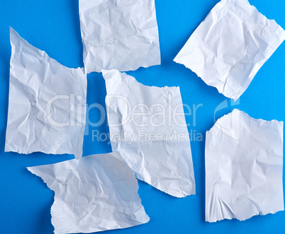 crumpled empty torn pieces of white paper on a blue background