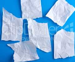 crumpled empty torn pieces of white paper on a blue background