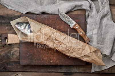 Fresh whole sea bass fish wrapped in a brown paper