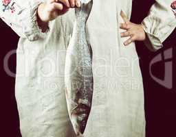 woman in gray linen clothes holding a fresh sea bass fish