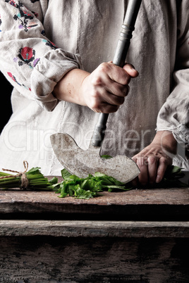 woman in a gray linen dress is cutting green leaves of fresh sor