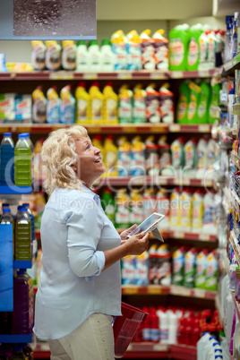 A smiling middle aged woman in a household section of a supermarket