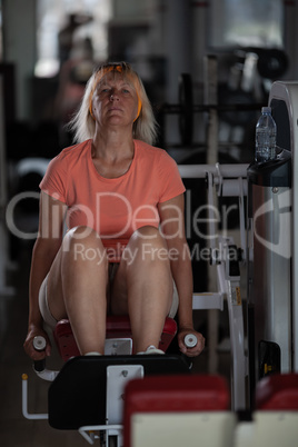 A middle aged woman in a gym on one of the training machines