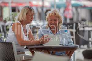 Senior women relaxing in cafe and using digital tablet