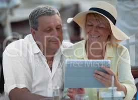 Cheerful mature couple with touch pad outdoor