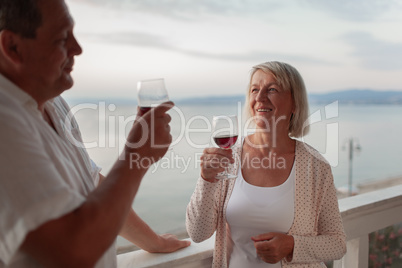 A smiling middle aged couple on a terrace close to the sea