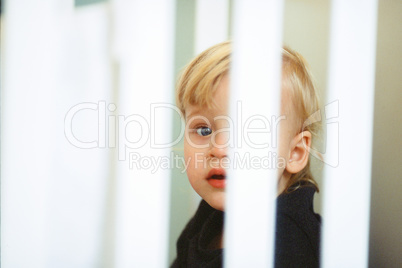 Baby girl portrait. View through the crib