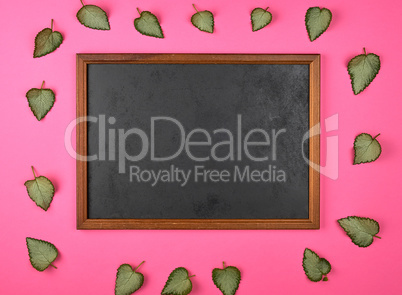 empty wooden frame on a pink background, decorating with green f