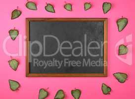empty wooden frame on a pink background, decorating with green f