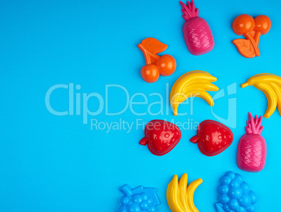 multicolored plastic toys fruits on a blue background