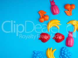 multicolored plastic toys fruits on a blue background