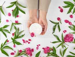 two female hands and a jar with thick cream and burgundy floweri