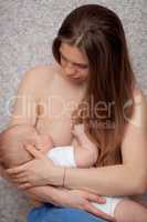 A long haired young woman breastfeeding a baby